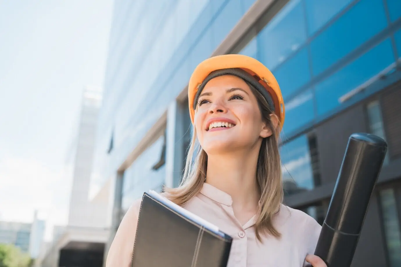 Portrait of a professional woman architect wearing a yellow helmet, standing outdoors. Engineering and architecture concept.